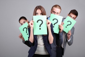 Business team standing in row with question mark on grey backgro